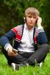 Student outside sitting on green grass and listening music via h