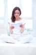 American or european young pretty woman sitting on bed in bright