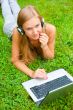 A smiling young girl with laptop outdoors listening music by hea