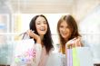 Two excited shopping woman together inside shopping mall. Horizo
