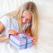 Bedroom surprise present - young happy woman in bedroom