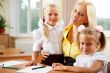 Young pretty teacher helping her little students in classroom