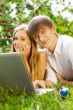 College students using laptop on campus lawn