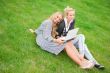 Portrait of two smiling women using laptop on a green meadow at 