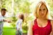 Upset teenage girl being jeered by group of the other young peop