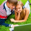 Happy young couple using laptop while lying on </spa