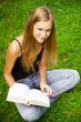 Beautiful female student outdoors with a book at campus park