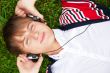 Student outside laying on grass and listening