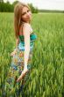 Portrait of young woman stands in a field of wheat with joy