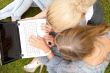 Portrait of two smiling women using laptop on a green meadow at 