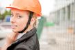 Young architect-woman wearing a protective helmet standing on th