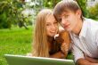 College students using laptop on campus lawn