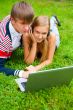 Happy young couple using laptop while lying on grass