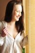 Portrait of cosy young girl standing near a window at home