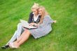 Portrait of two smiling women using laptop on a green meadow at 