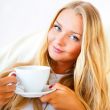 Young woman at home sipping tea or coffee from a cup