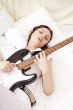 Teen girl holding a guitar like a rock star and enjoying playing