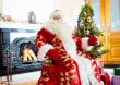 Santa sitting at the Christmas tree, fireplace and looking at ca