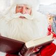 Santa sitting at home and reading a book. Indoors