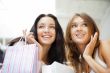 Two excited shopping woman together inside shopping mall. Horizo