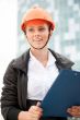 Young architect-woman wearing a protective helmet standing on th