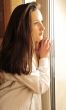 Portrait of cosy young girl standing near a window at home