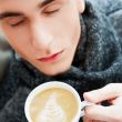 Portrait of a young man drinking coffee while sitting on armchai