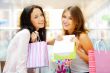 Two excited shopping woman together inside shopping mall. Horizo