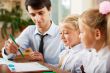 Teacher helping students with schoolwork in school classroom. Ho