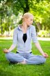 Portrait of young woman meditating in pose of lotus on green gra