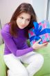 Delighted woman opening a gift sitting on the bean bag at home