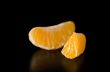 Close up photograph of a juicy Clementine orange slice on a blac