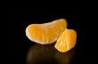 Close up photograph of a juicy Clementine orange slice on a blac