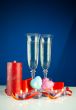 Two wineglasses and burning candles against blue background