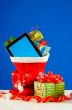 Tablet PC with heap of presents in red bag against blue backgrou