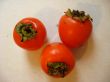 three beautiful ripe persimmons laying on a table