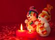 Two snowmen with two burning heart shaped candles