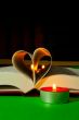 Open book with burning candle
