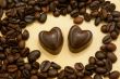 Two heart shaped chocolate candies and coffee beans