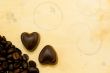 Two heart shaped chocolate candies and coffee beans