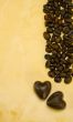 Two heart shaped chocolate candies and coffee beans