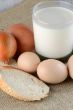 Chicken eggs with slices of bread on the table with milk