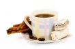 Coffee cup with sweets an cinnamon on white background