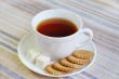A cup of tea with biscuits and slices of sugar