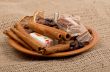 Sweets, cinnamon, nuts and coffee beans on a saucer, on burlap b