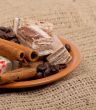 Sweets, cinnamon, nuts and coffee beans on a saucer, on burlap b