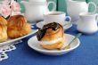 Ã‰clair with chocolate frosting on a plate with a cup of coffee
