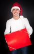 Smiling man in Santa hat gives a red box in the studio