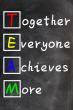 TEAM acronym (Together Everyone Achieves More), teamwork motivation concept of chalk handwriting on a blackboard