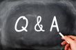 Question and Answer written on a blackboard with a hand holding chalk